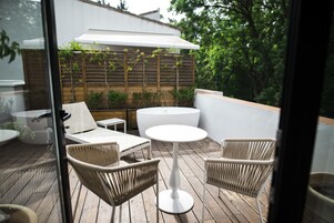 Una terrazza esterna con mobili in vimini, un tavolo rotondo e un ombrellone bianco.