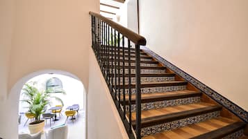 A staircase with ornate railings and patterned steps, leading to a balcony area with outdoor seating and a potted plant.