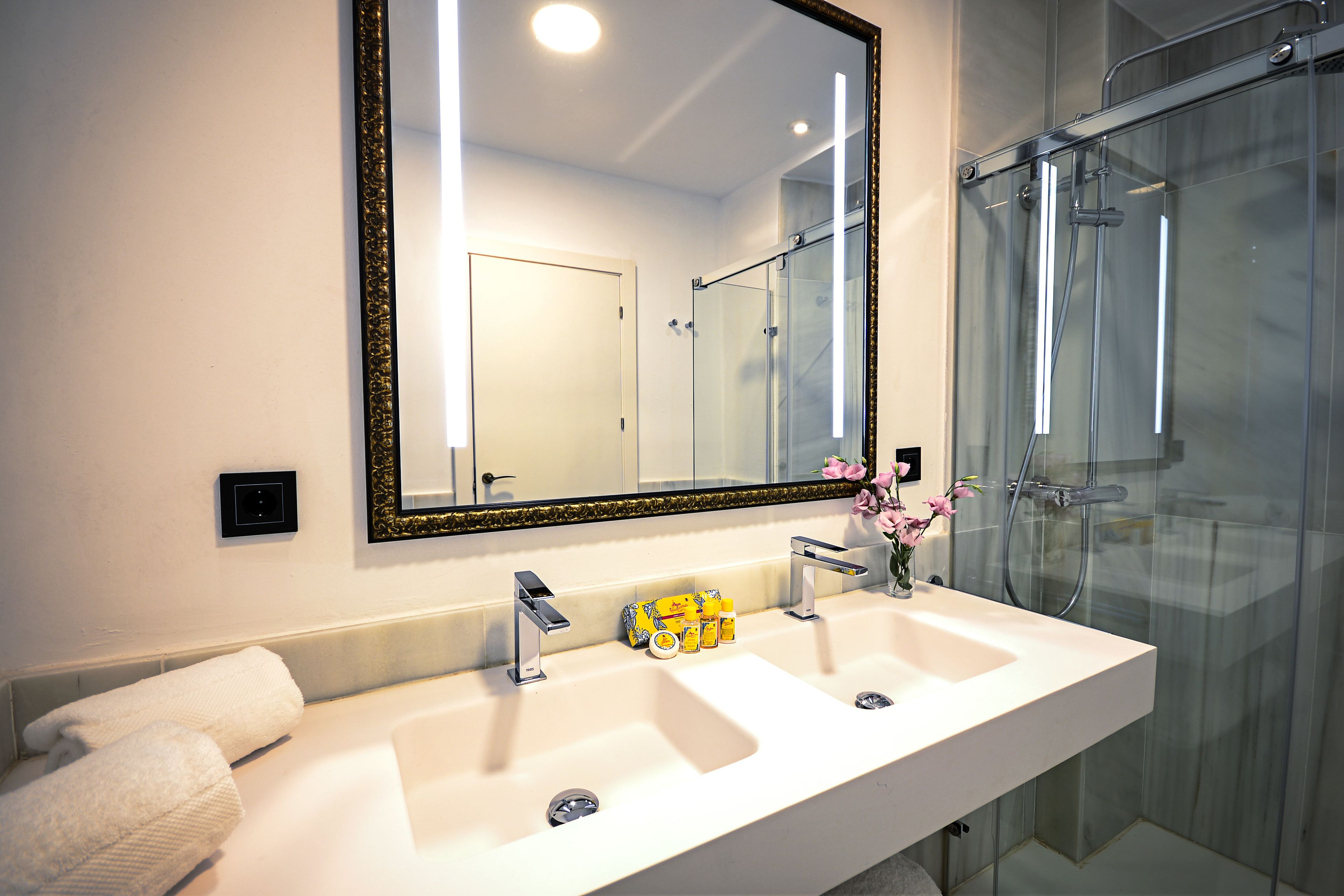 A bathroom with a large mirror, two sinks, and a glass shower enclosure.