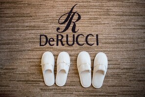 A wooden floor with the text "R DeRUCCI" and four white slippers arranged in a row. - DeRUCCI Hotel (Dongguan)