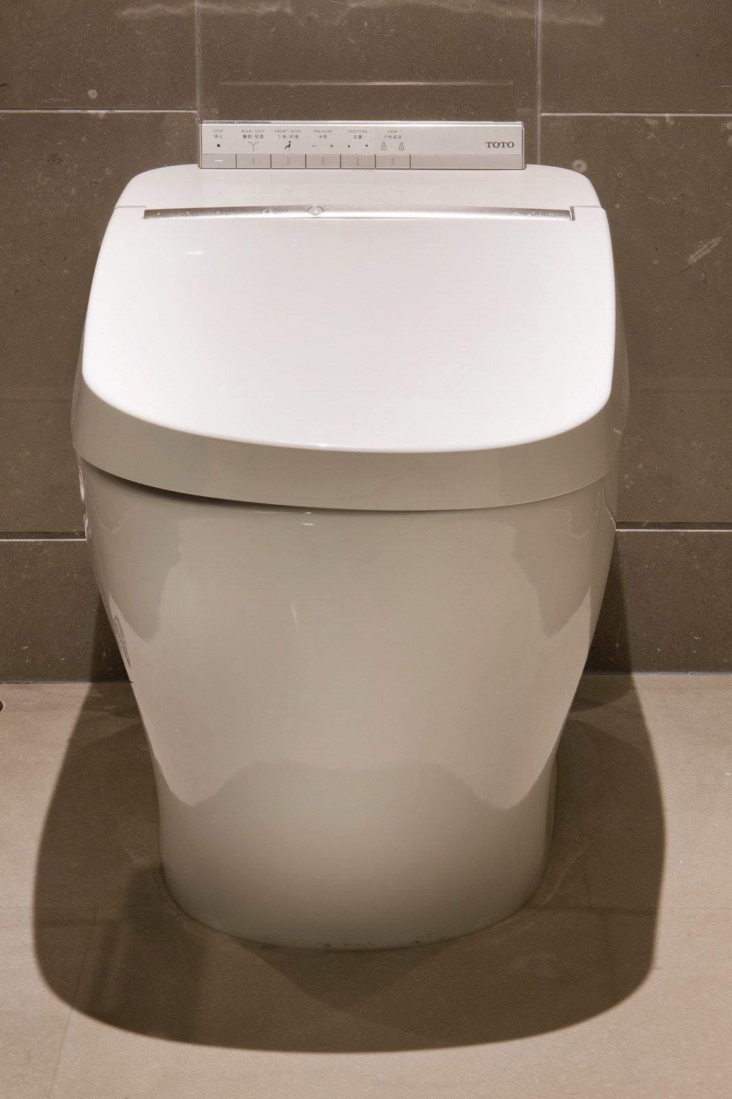 A modern toilet with a control panel featuring multiple buttons and a brand name.