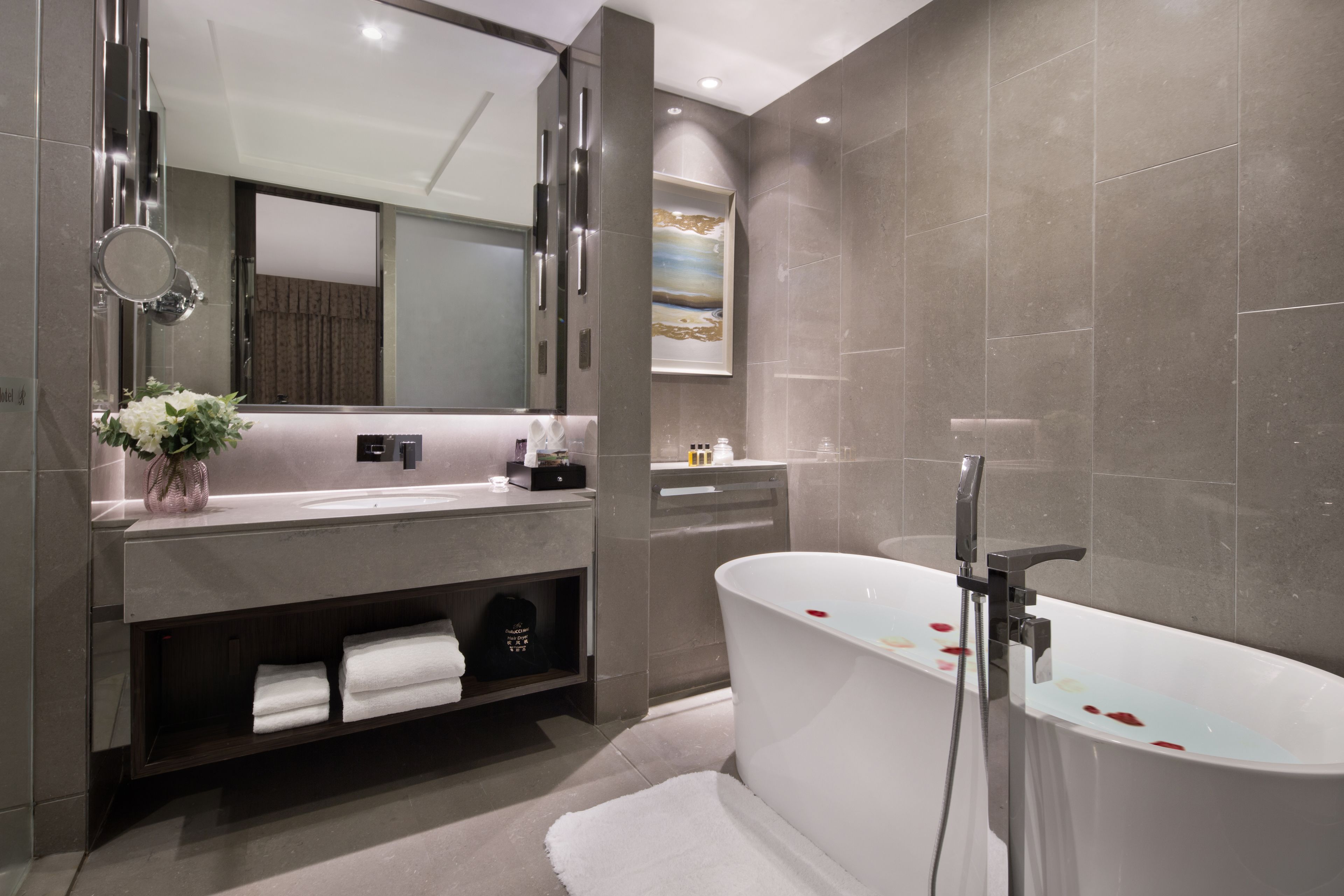 Une salle de bain moderne avec une baignoire sur pieds, un grand miroir et un meuble-lavabo doté d’un porte-serviettes.