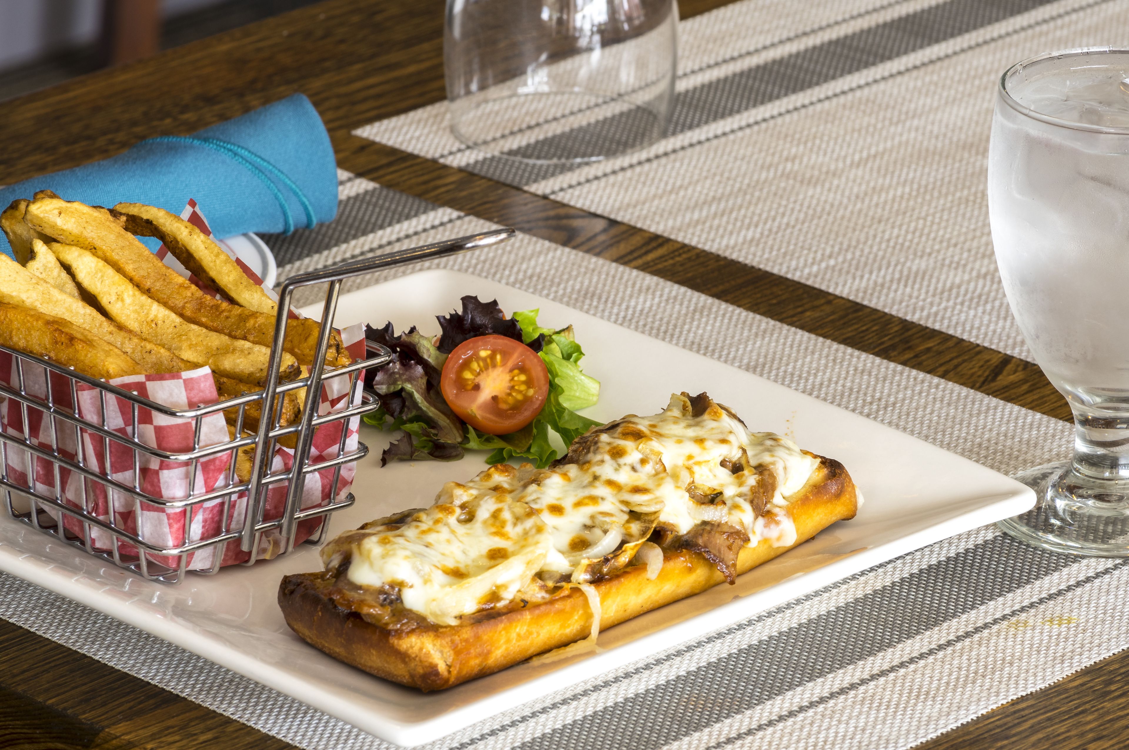 A meal consisting of a sandwich, fries, and a salad on a table with a placemat.