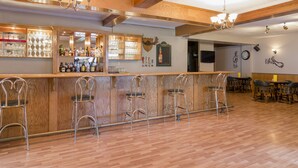 Zona de bar con vigas de madera, mostrador y sillas de metal.