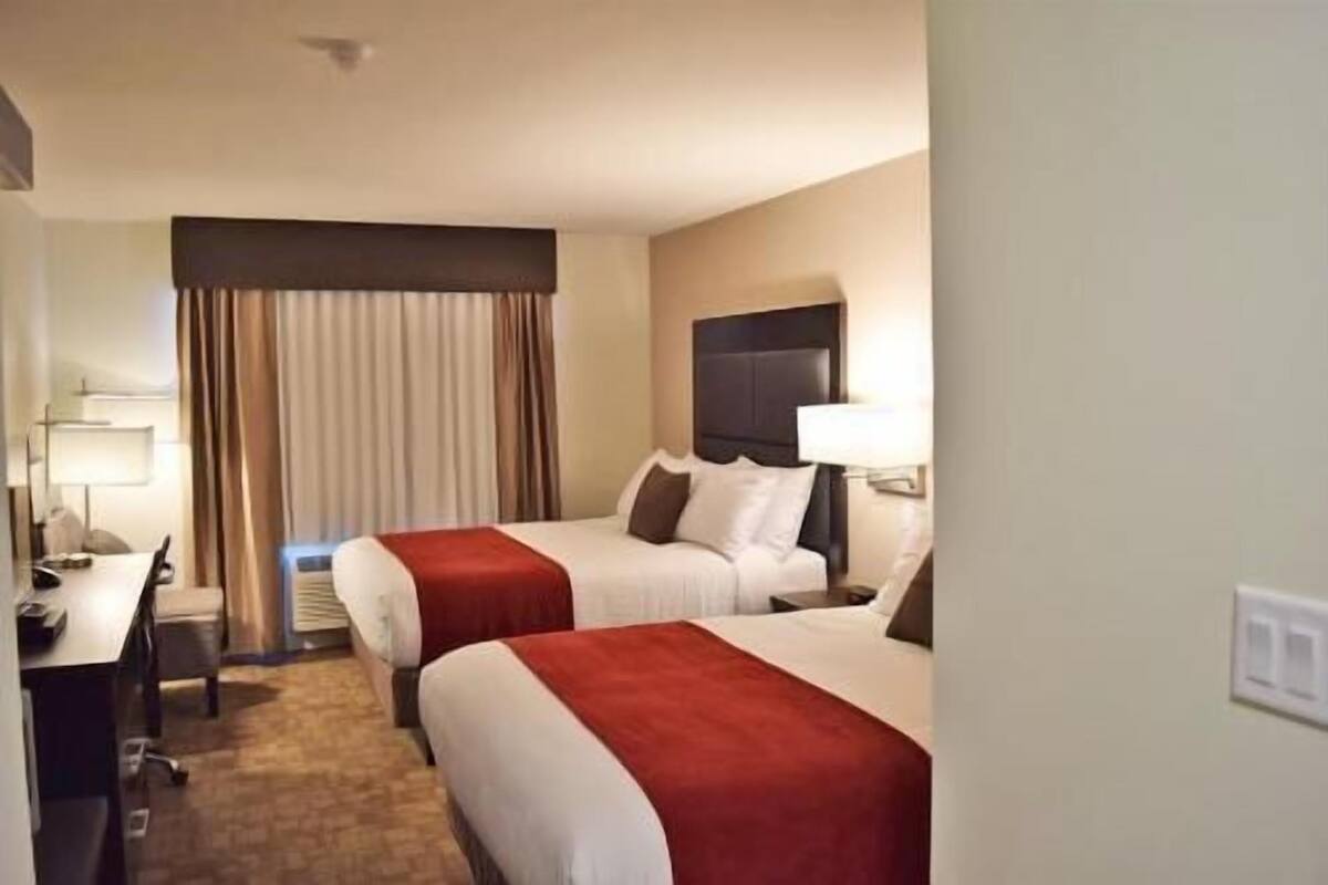 Une chambre d’hôtel avec deux lits, un bureau et une chaise.