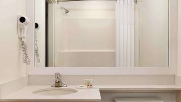 A bathroom with a large mirror, a sink, a toilet, and a shower.