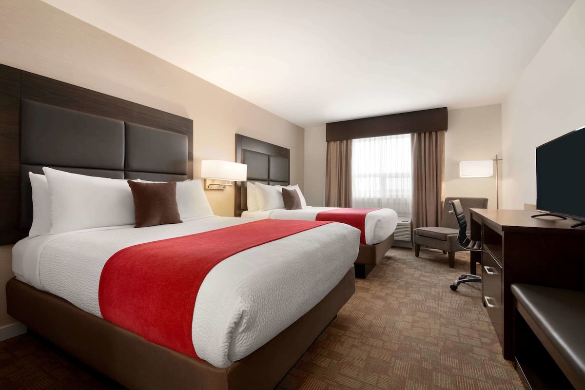 Une chambre d’hôtel avec deux lits, un bureau, une chaise et un téléviseur.
