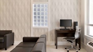 Un espace de bureau moderne doté d’une grande fenêtre, d’un bureau avec un ordinateur et de deux canapés.
