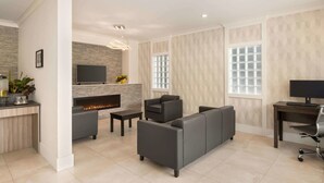 Un salon moderne avec une cheminée, des canapés gris, un téléviseur et un bureau avec un ordinateur.