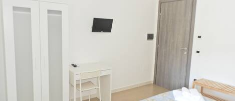 Un dormitorio con cama, escritorio, silla y armario.