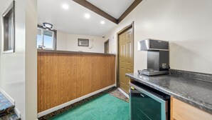 Cozinha compacta com micro-ondas embutido, lava-louças e parede revestida de madeira.