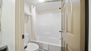 Un baño con inodoro, bañera y cortina de ducha.