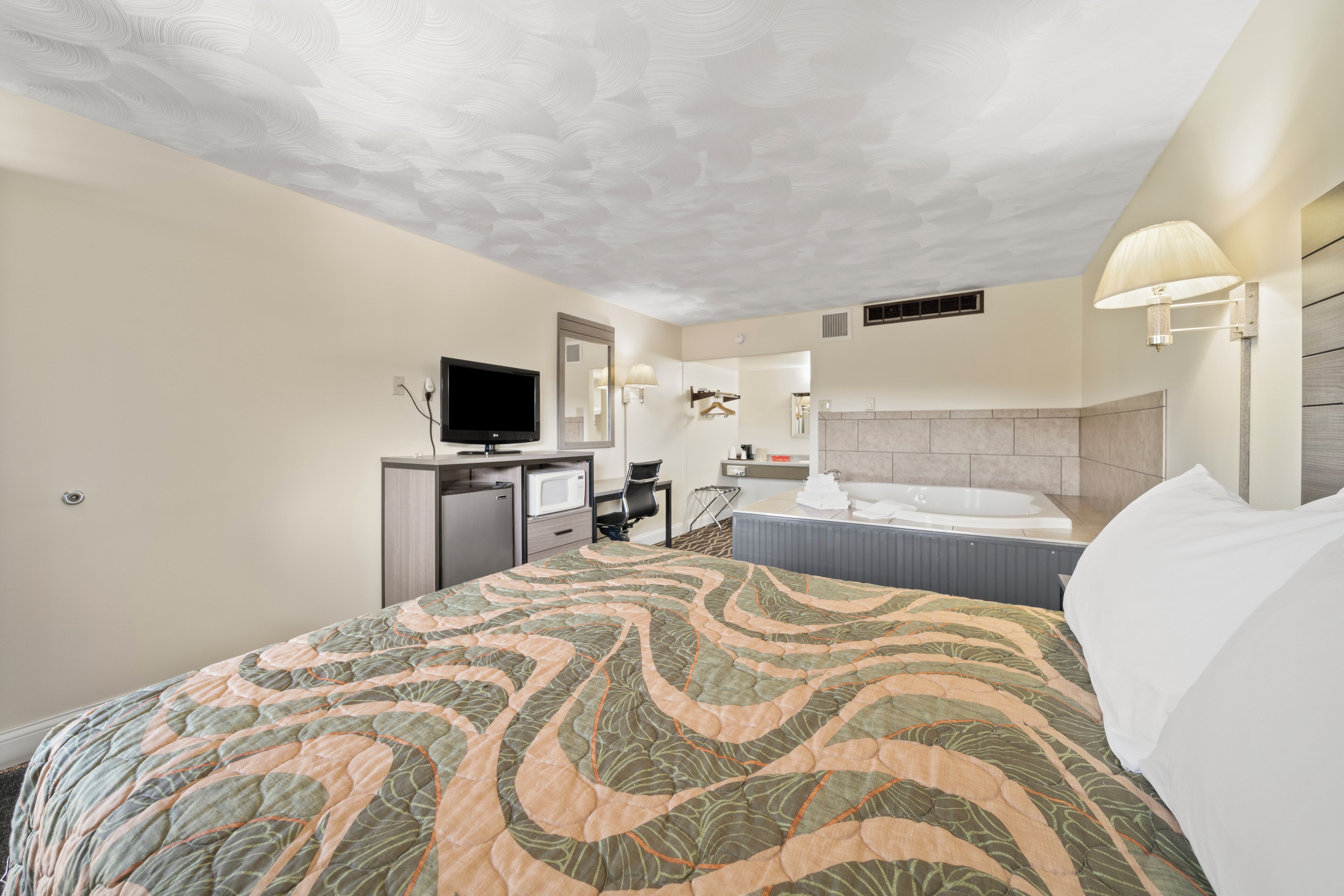 A hotel room with a large bed, a television, a desk, and a bathroom.