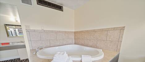 A modern bathroom with a freestanding bathtub, a vanity with a mirror, and a patterned rug on the floor.