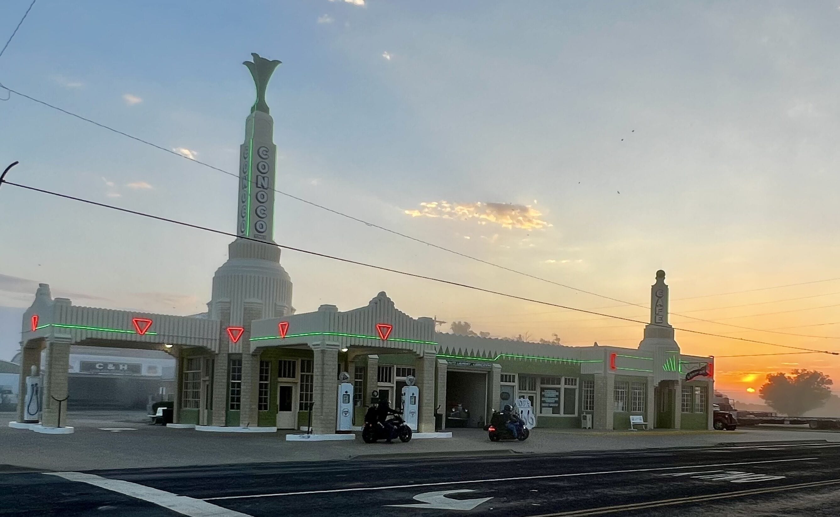 A gas station with a tall, narrow building and a smaller structure with a sign.