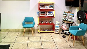 A room with two blue chairs, a wall clock, a Route 66 sign, and a television. - Western Motel (Shamrock)