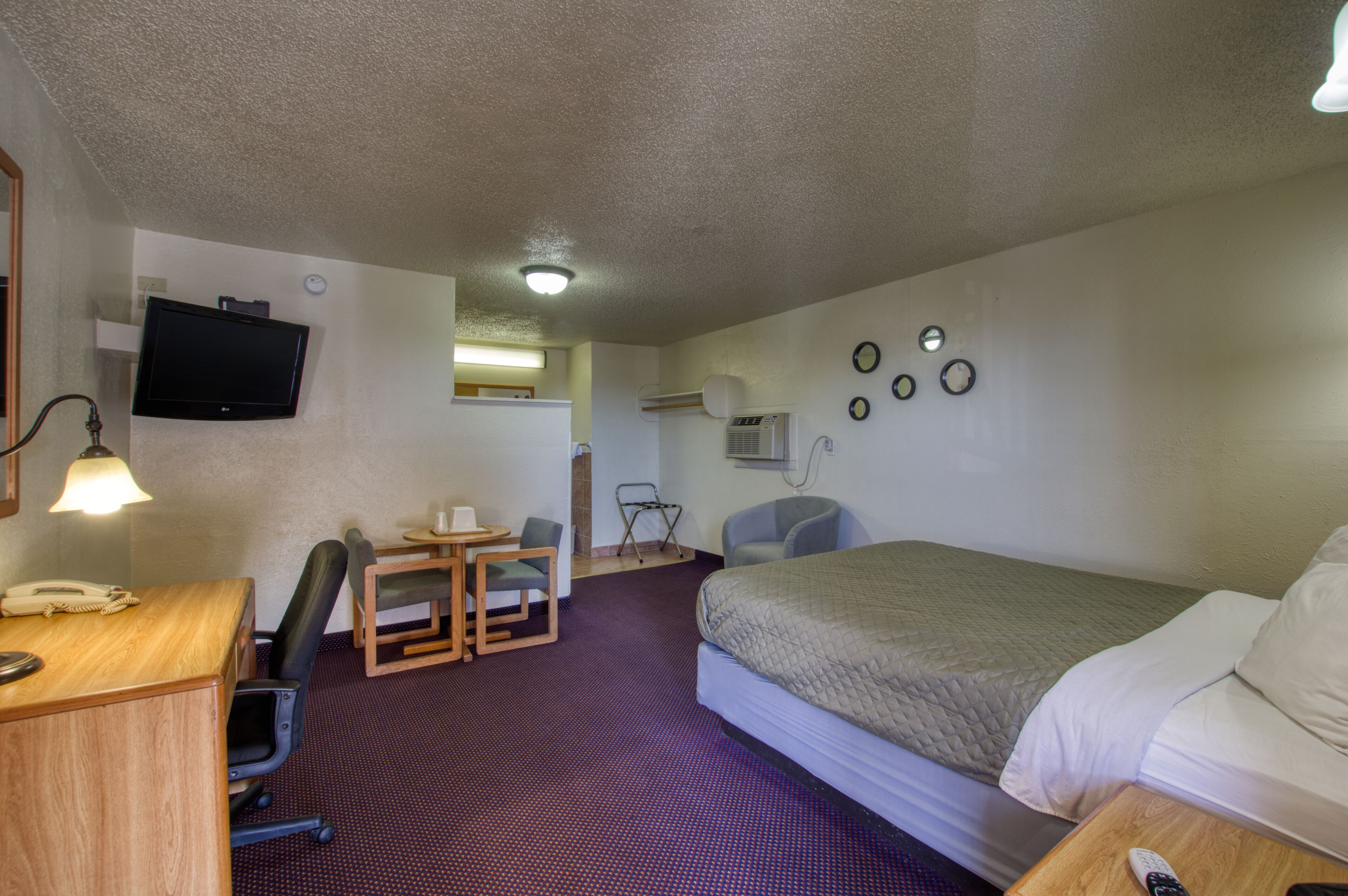 A hotel room with a bed, desk, chair, and television.