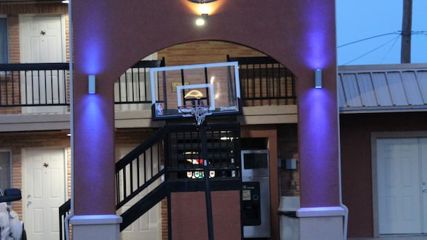 A building with a basketball hoop under a purple-lit archway. - Western Motel (Shamrock)