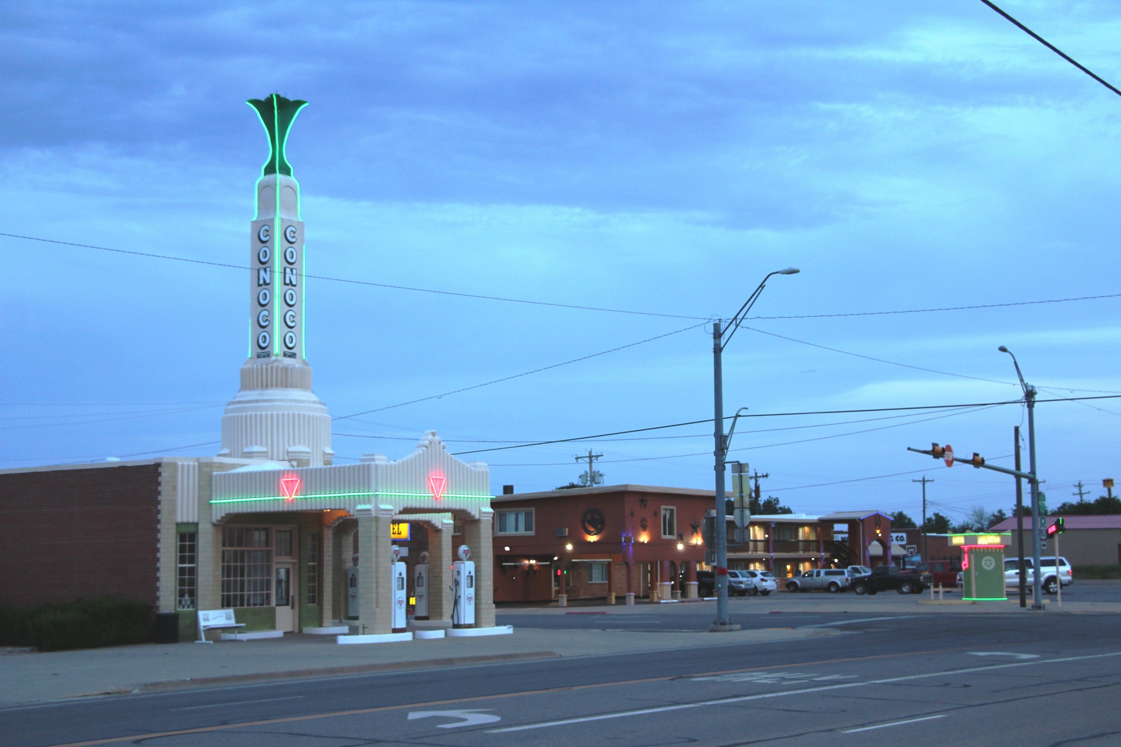 A building with a prominent tower and neon signs, including a gas station with a red neon sign.