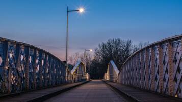 Een metalen brug met een houten looppad en lantaarns.
