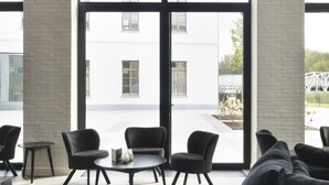 Un intérieur moderne avec de grandes fenêtres, des meubles noirs et un mur en briques blanches.