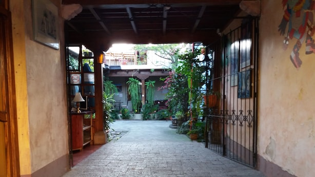 A paved pathway leading to a gated area with potted plants and a wooden structure. - Hotel Dionisio Inn (Antigua Guatemala)