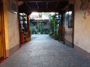 A paved pathway leading to a gated area with potted plants and a wooden structure. - Hotel Dionisio Inn (Antigua Guatemala)