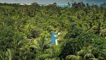 Un resort tropical con abundante vegetación, una piscina y vistas al océano.