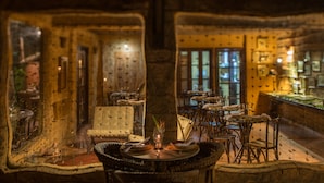 A dimly lit restaurant with rustic decor, including stone walls and wooden furniture. - Toca da Coruja - Eco Luxury Retreat (Tibau do Sul)