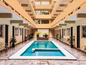 A pool area with a rectangular pool, potted plants, and a tiled floor.