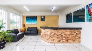 Un vestíbulo moderno con un sofá de cuero negro, una recepción con pared de ladrillo y un ventanal con vistas al exterior.