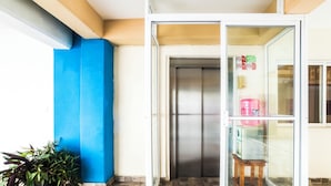 Una habitación con una puerta corrediza de vidrio que da a un balcón, una planta en maceta y suelo de baldosas.