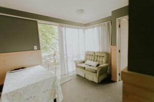 Una habitación con una cama, una mesa, una silla y una ventana con cortinas.