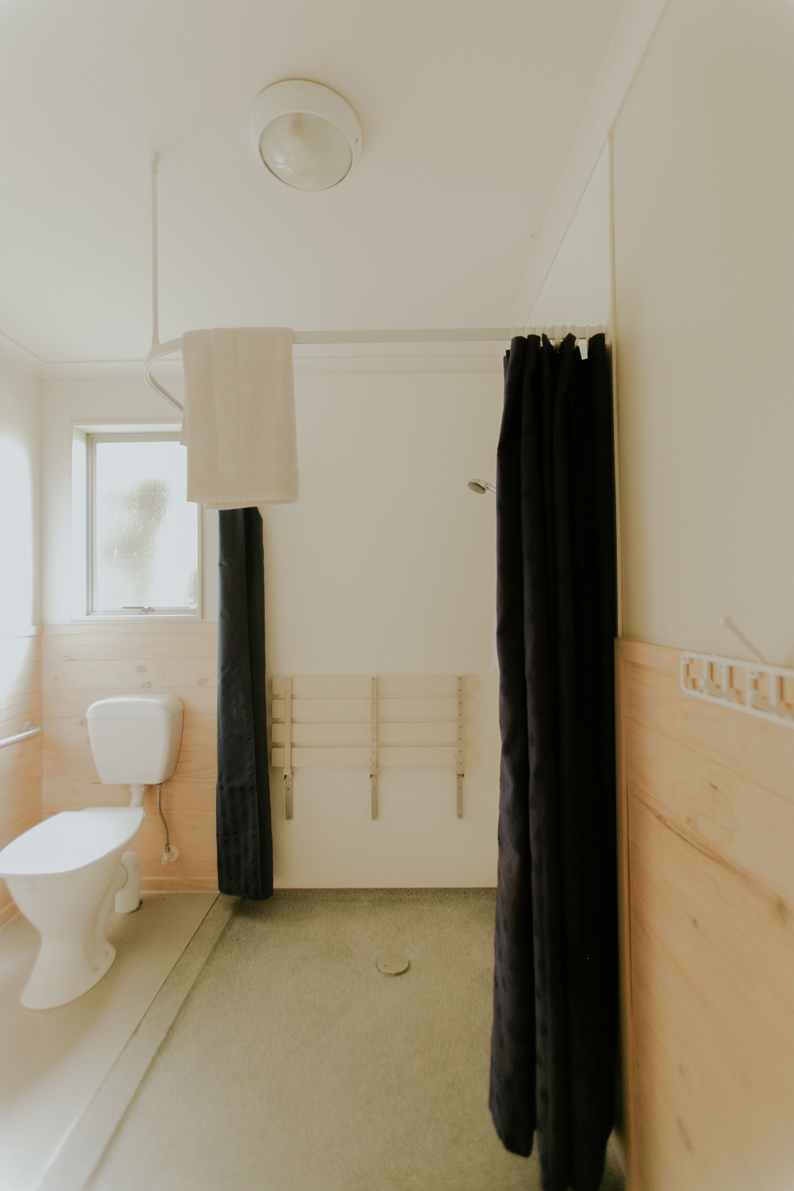 A bathroom with a toilet, a shower curtain, and a towel rack.