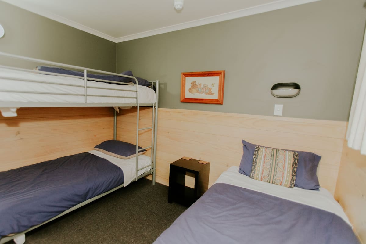 A room with bunk beds, a small table, and a framed picture on the wall.