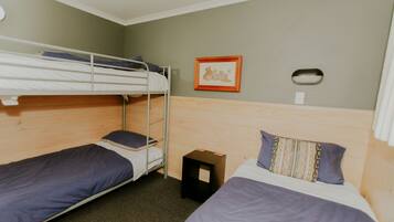 A room with bunk beds, a small table, and a framed picture on the wall.