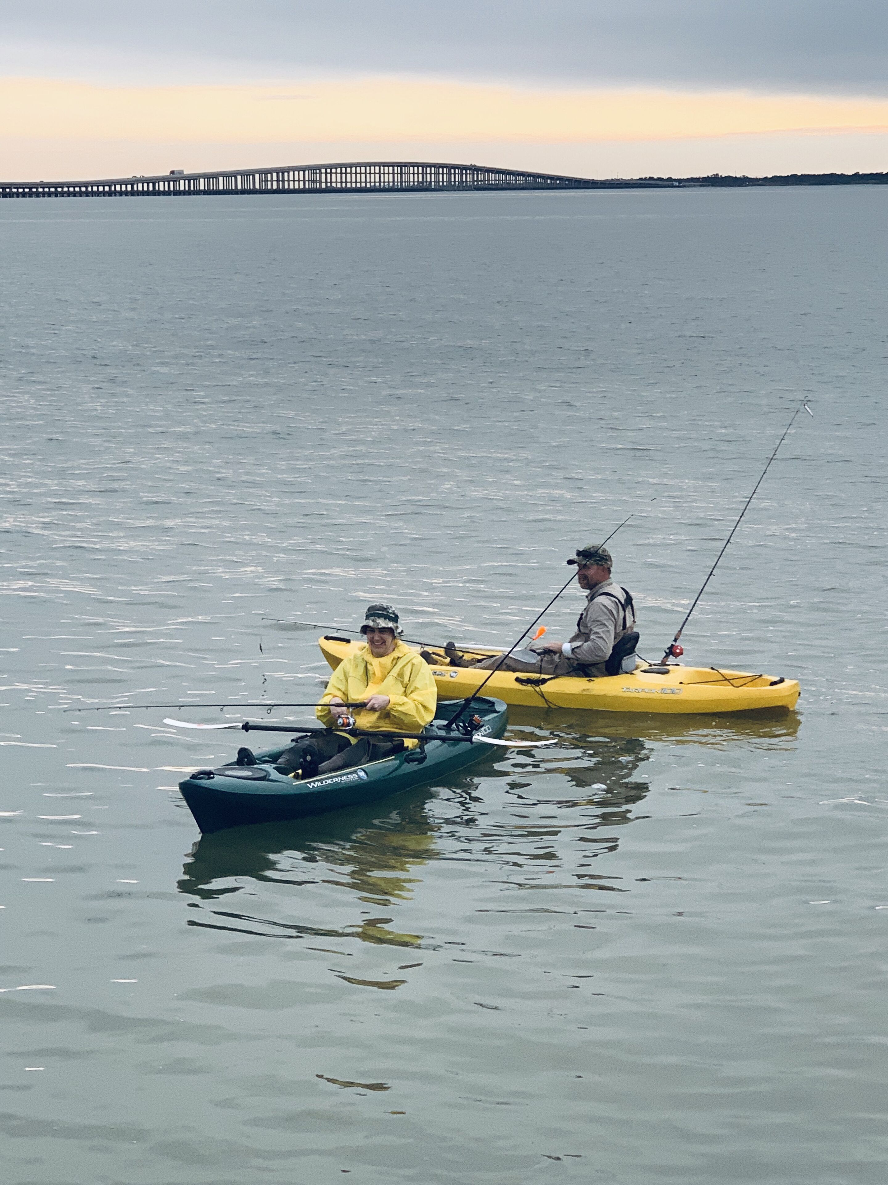 Two kayaks on calm water with a pier in the background.