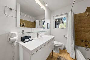 A modern bathroom with a white sink, a glass shelf, a toilet, and a shower area. - SocoVilla: Downtown/Pool/Golf Green/FirePit/18 Beds (Austin)