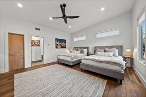 A bedroom with two beds, a ceiling fan, recessed lighting, a large window, and artwork on the walls. - SocoVilla: Downtown/Pool/Golf Green/FirePit/18 Beds (Austin)