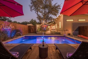 A backyard with a swimming pool, wooden deck, lounge chairs, and a wooden fence. - SocoVilla: Downtown/Pool/Golf Green/FirePit/18 Beds (Austin)