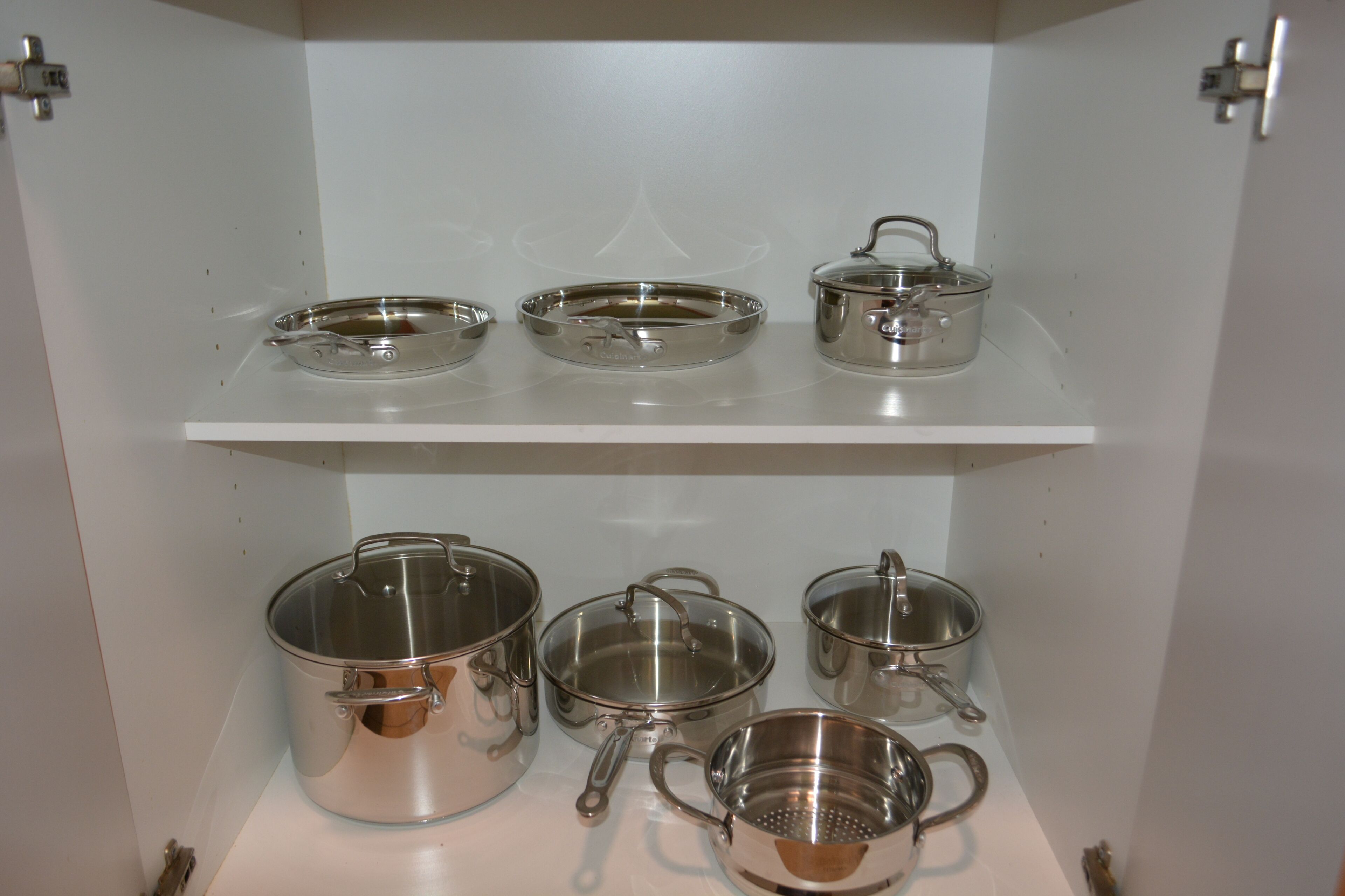Een keuken met roestvrijstalen pannen en keukengerei op planken.