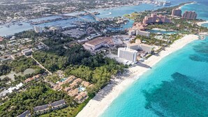 Vue aĂ©rienne dâune zone balnĂ©aire, avec des propriĂ©tĂ©s situĂ©es en bord de mer, un port de plaisance et plusieurs hĂŽtels de grande hauteur.