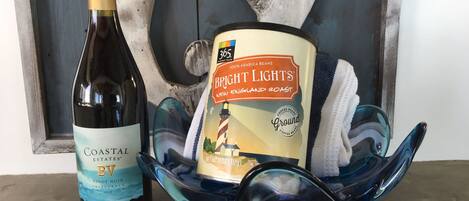 A bottle of Coastal Estates BV Pinot Noir and a can of Bright Lights New England Roast coffee beans on a blue glass dish.