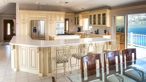 A spacious kitchen with a large island, stainless steel appliances, and a view of the ocean. - East End Overlook, 3 Acre Ridgetop Estate with Dual Shore Views (Saint Croix)