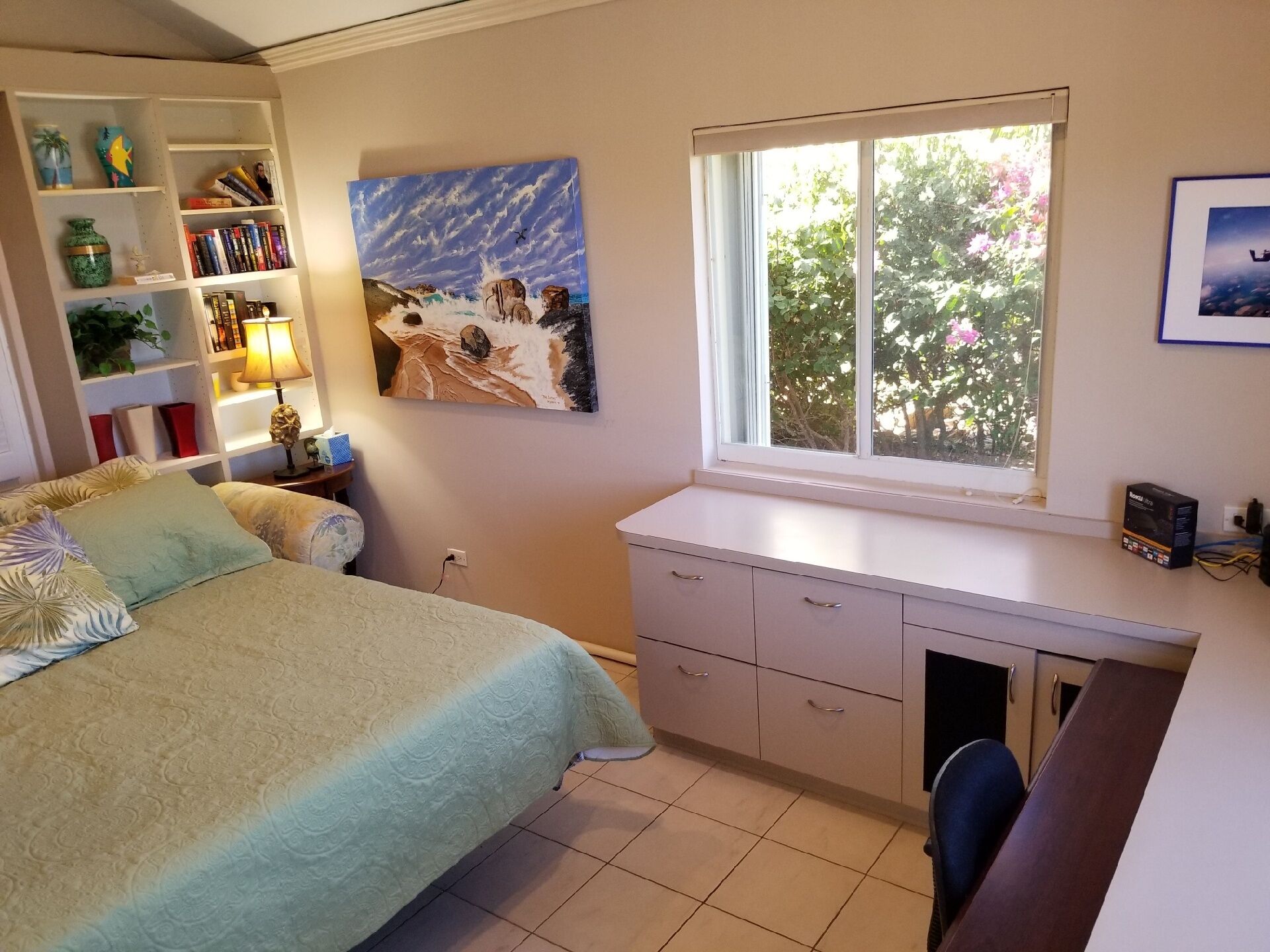 Un dormitorio con cama, escritorio, ventana y estantería.