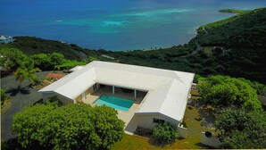 A modern house with a swimming pool, surrounded by lush greenery and overlooking a turquoise sea. - East End Overlook, 3 Acre Ridgetop Estate with Dual Shore Views (Saint Croix)