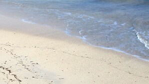 A beach with clear water, a sandy shore, and a distant island. - East End Overlook, 3 Acre Ridgetop Estate with Dual Shore Views (Saint Croix)