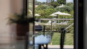 On peut apercevoir, à travers une paroi de verre, un espace piscine avec des chaises longues et des parasols.