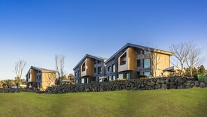 Un edificio residencial moderno de varios pisos con un muro de contención de piedra en primer plano.