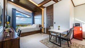Una habitación de hotel moderna con cama, una mesa de comedor y vista al océano.